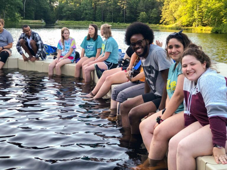 Staff and teens sitting on a dock