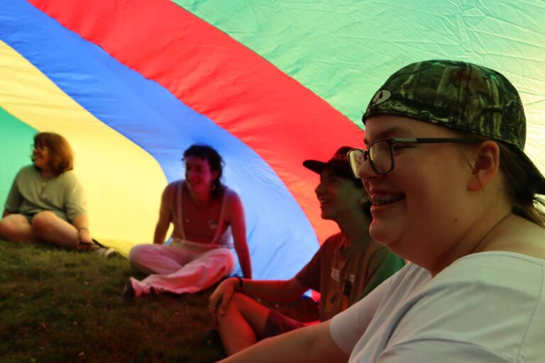 Campers under giant rainbow parachute