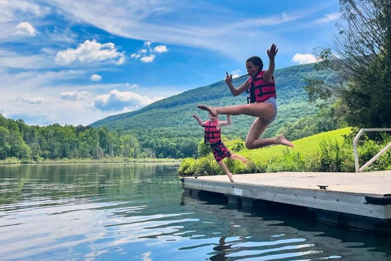 Campers jumping off dock into lake