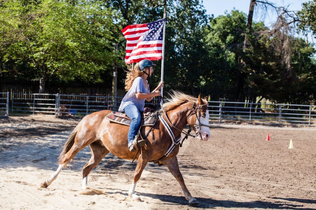 Camper riding horse holding flag