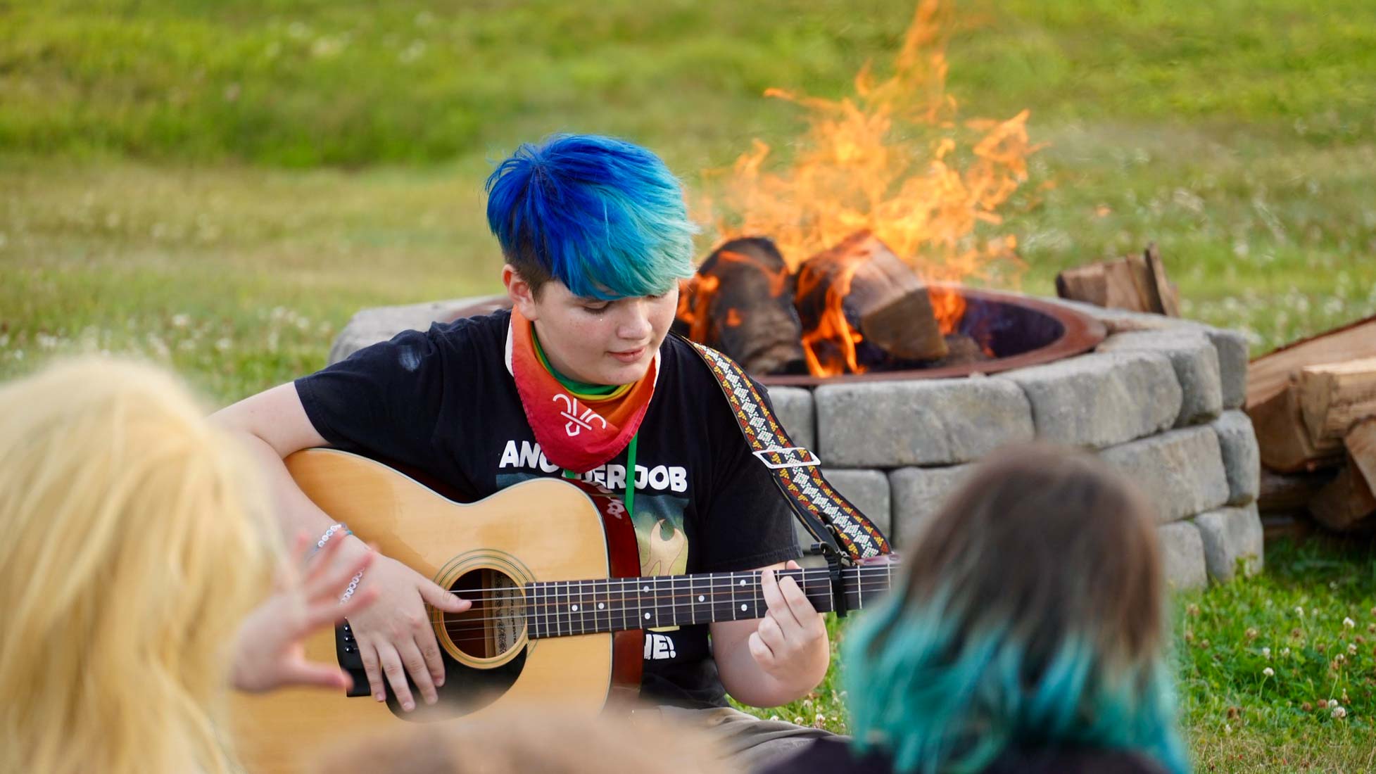 Camper playing guitar by camp fire
