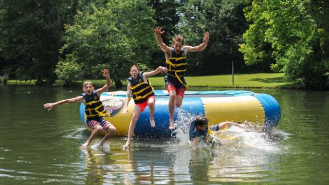 Campers jumping off water trampoline