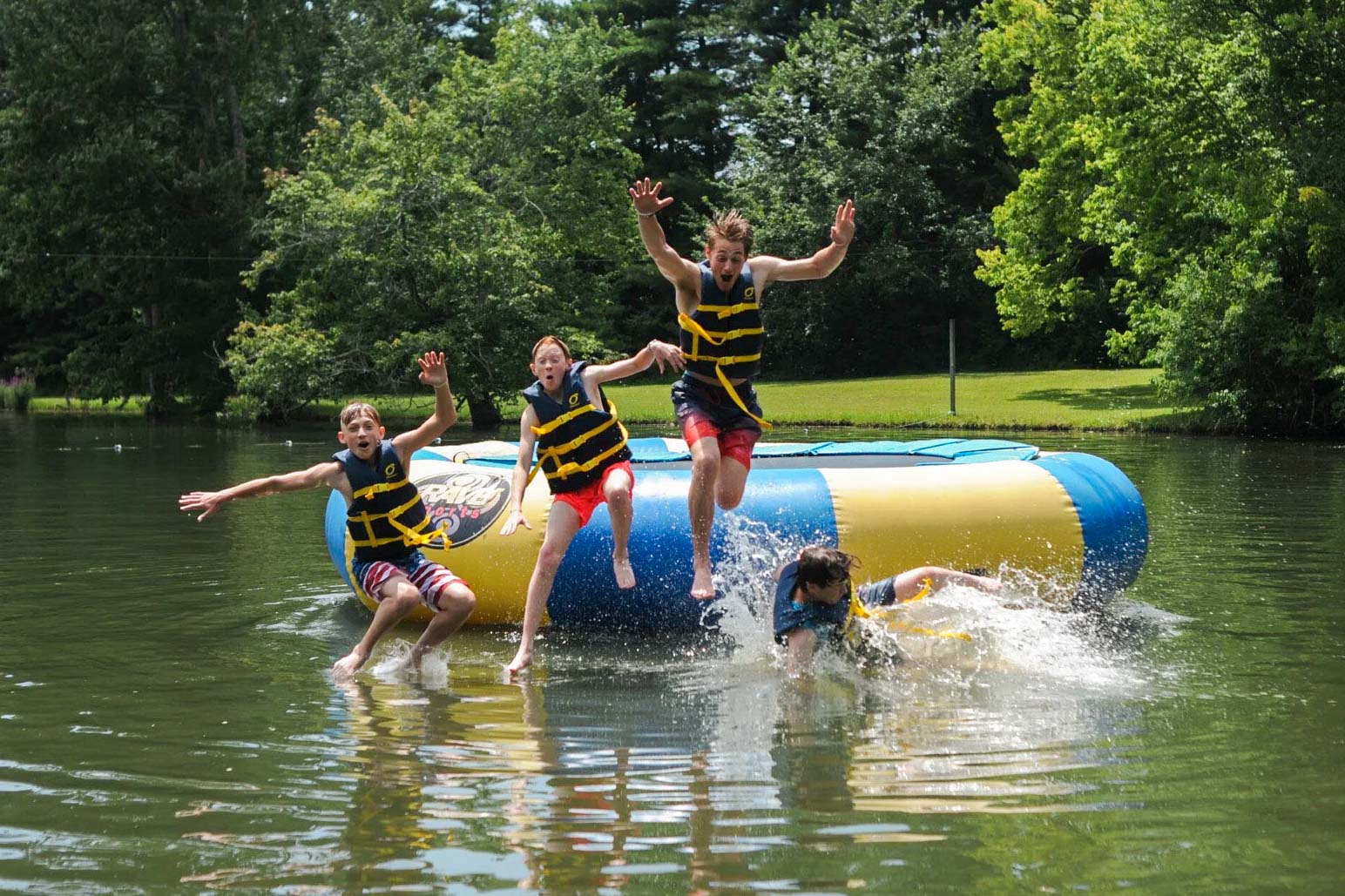 Campers jumping off water trampoline