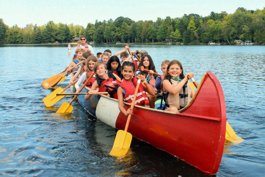 Group of kids paddling in a large canoe