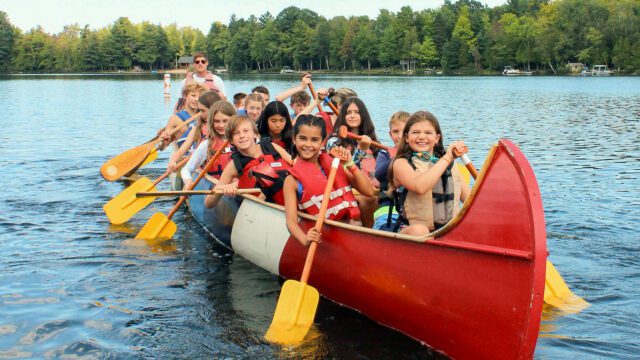 Group of kids paddling in a large canoe
