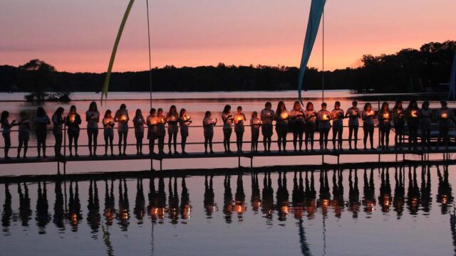 Girls holding candles on dock at sunet