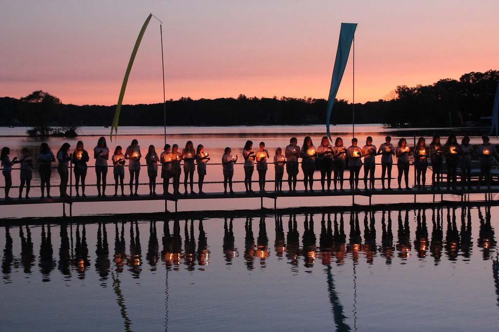 Girls holding candles on dock at sunet