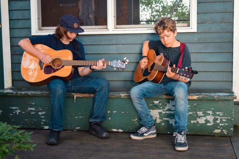 Two teen boys playing guitar together