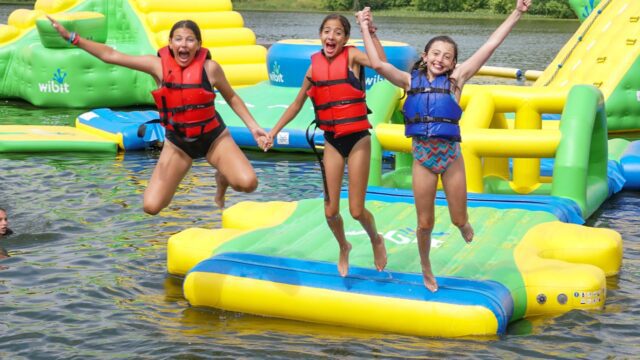 Three girls jumping into a lake together