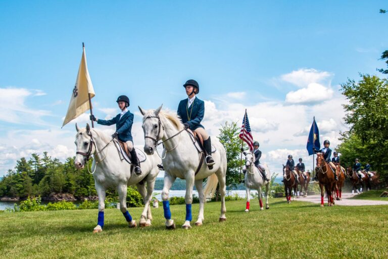 Campers riding horses holding flags