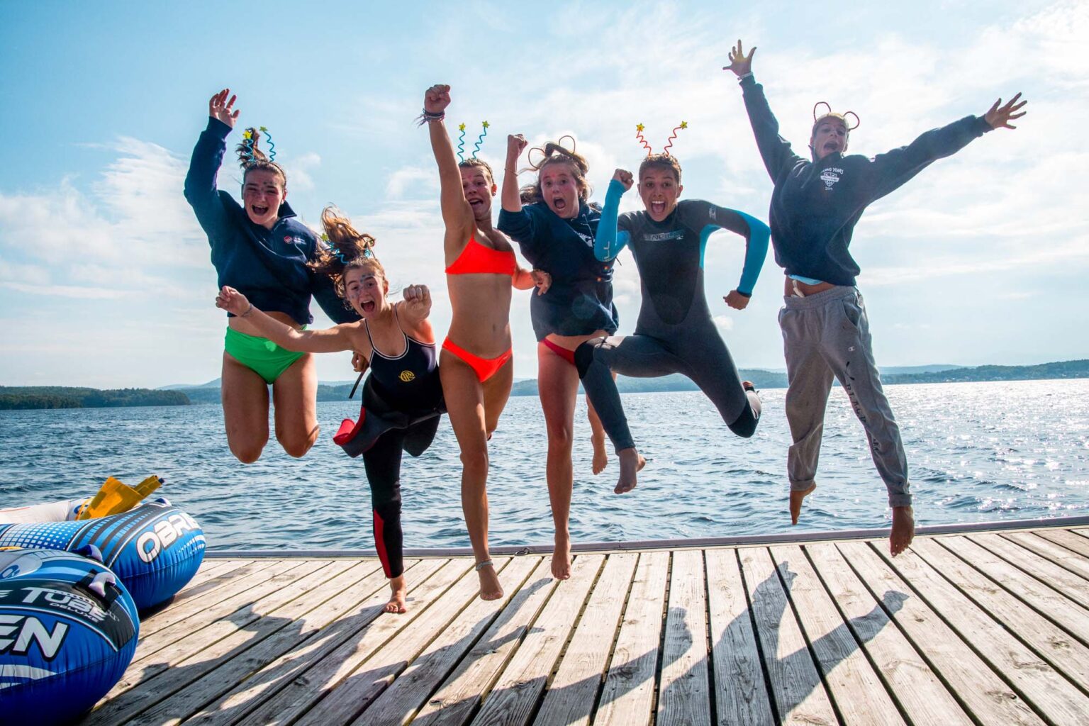 Happy girls jumping on dock