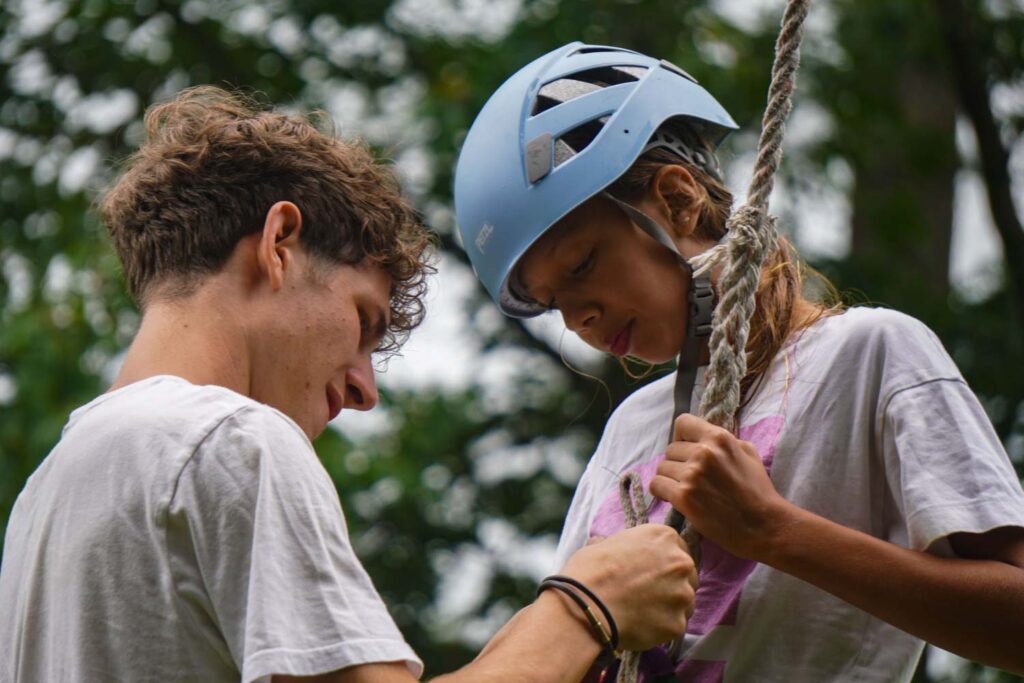 Counselor helping rock climbing camper