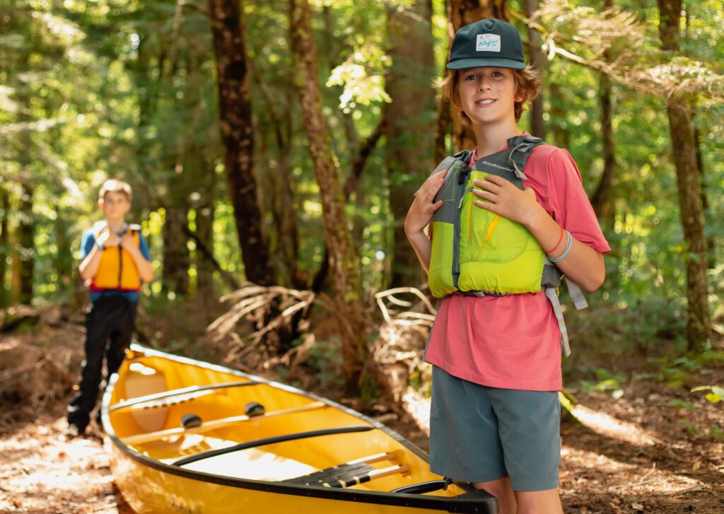 Two boys standing by a canoe