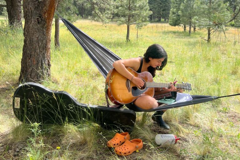 Girl playing acoustic guitar in hammock
