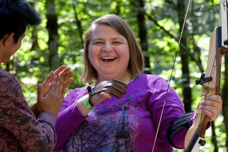 Smiling camper holding archery bow