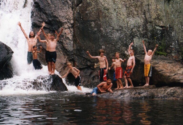 Boys swimming near waterfall