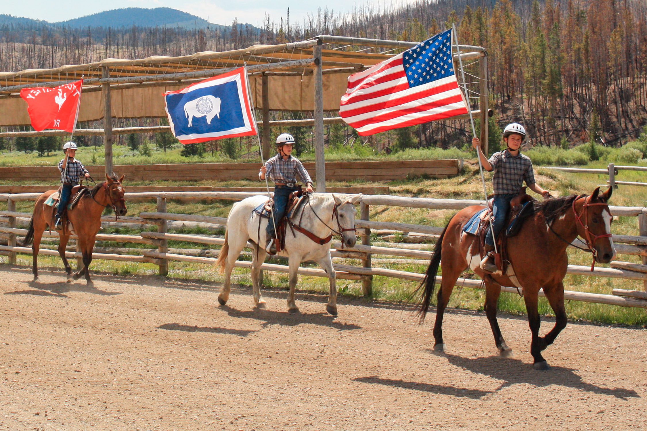 Campers riding horses holding flags