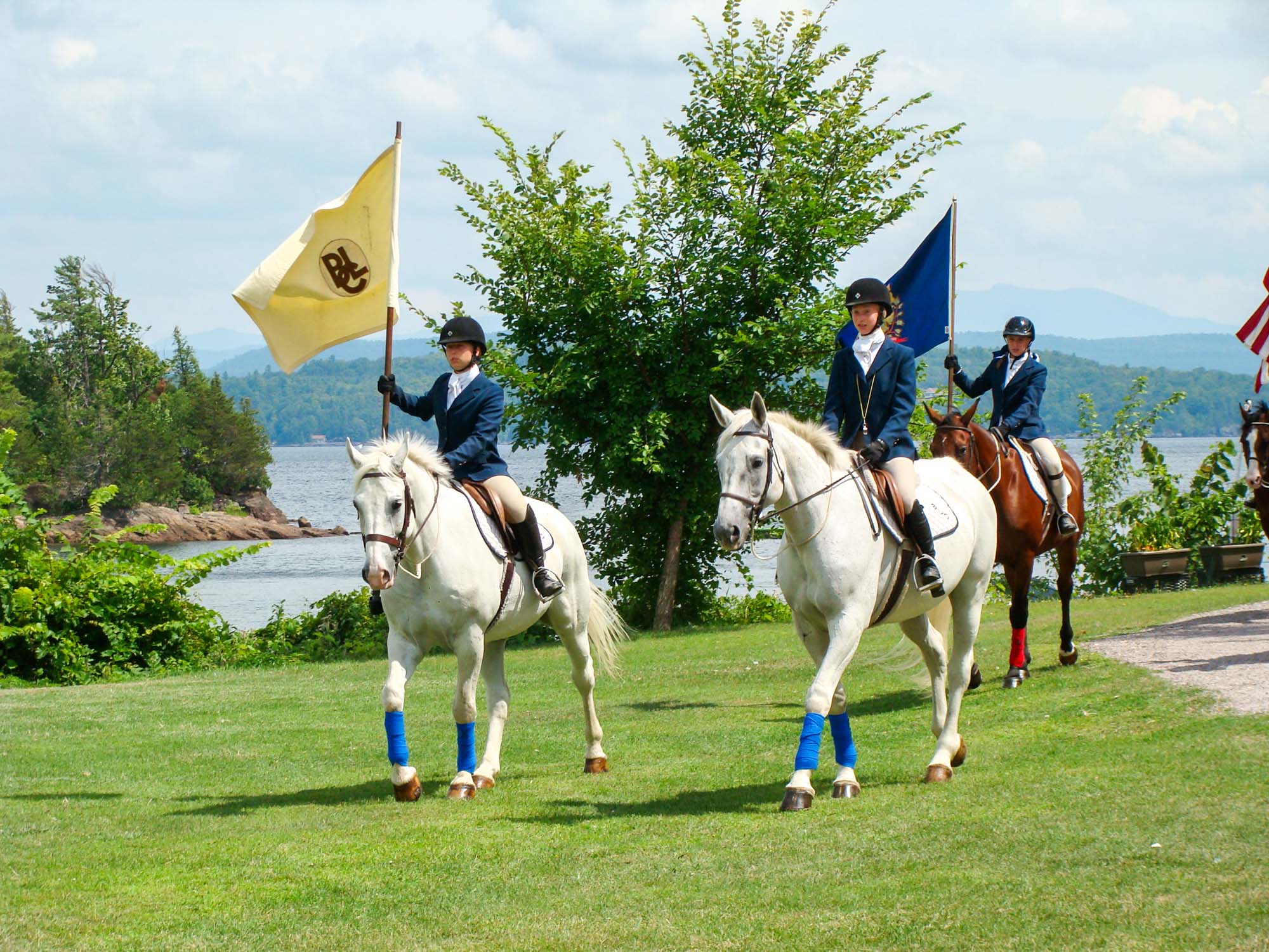 Equestrian girls riding horses hold flags