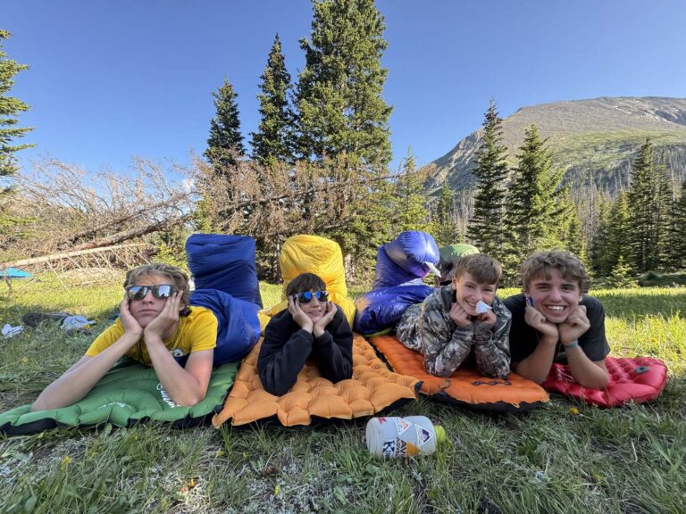 Four campers in sleeping bags looking at the camera