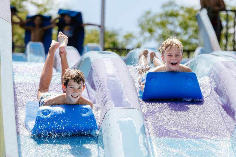 Two joyful boys riding down a waterslide